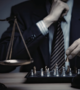 A set of scales and a chessboard, symbolising the balanced and strategic approach of human-led examination invigilation.
